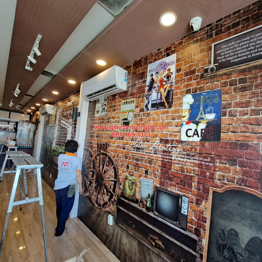 Thợ đang thi công dán tranh tường 3D giả gạch cổ phong cách vintage kết hợp hình ảnh poster Retro cho không gian quán cafe.