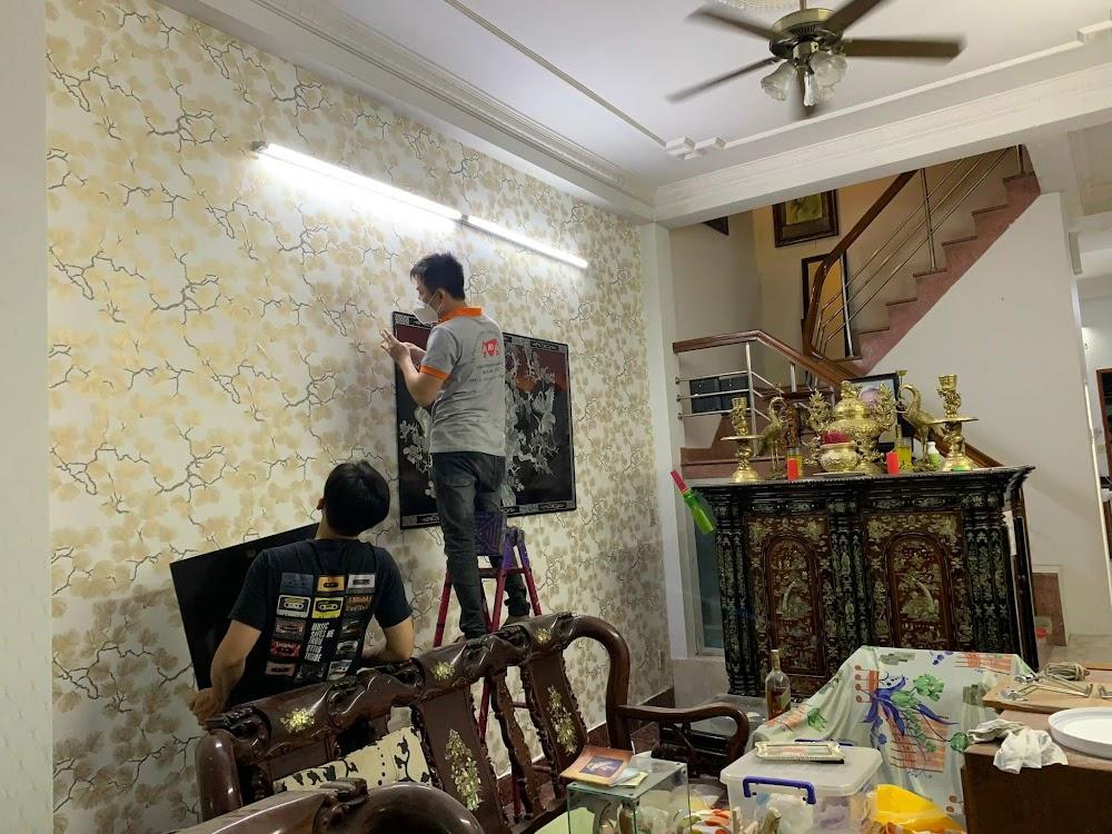 Thợ đang đo đạc và thi công dán giấy dán tường họa tiết hoa văn cổ điển sang trọng cho phòng khách.