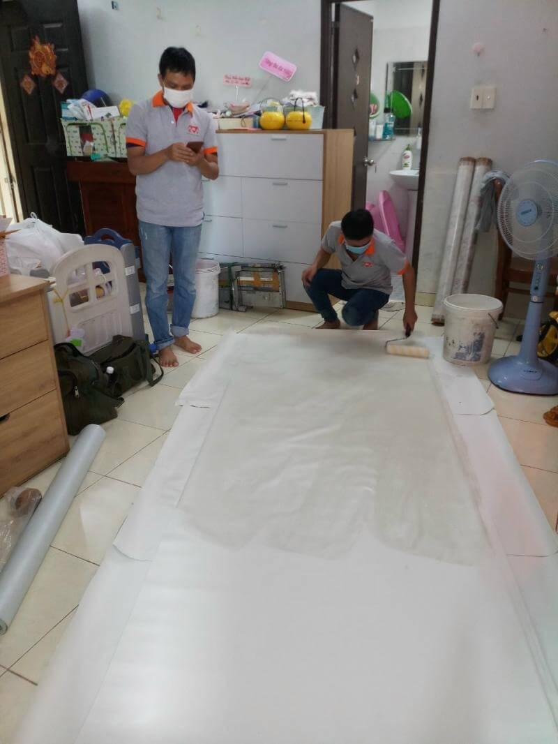 Thợ tiến hành phủ keo cho giấy trước khi dán