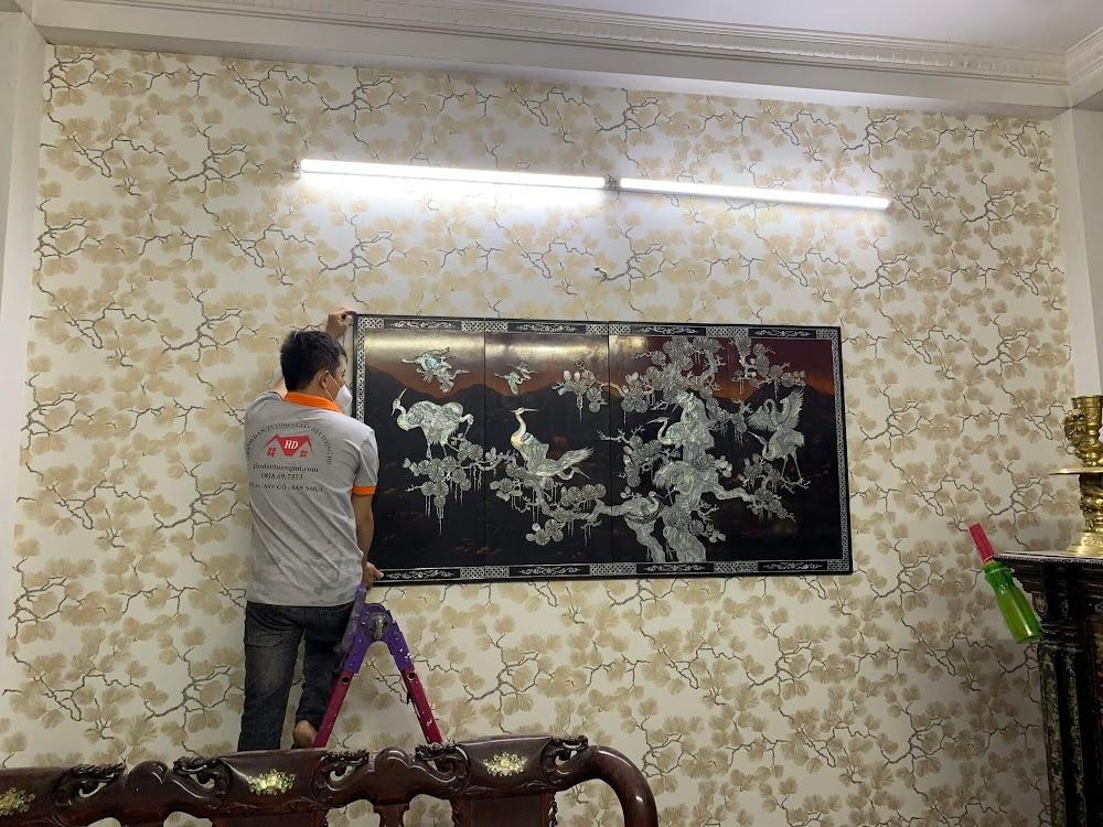 Bức tranh khảm trai bừng sáng trên nền giấy dán tường giả vải nhã nhặn, giúp luân chuyển năng lượng phong thủy tích cực cho phòng khách.