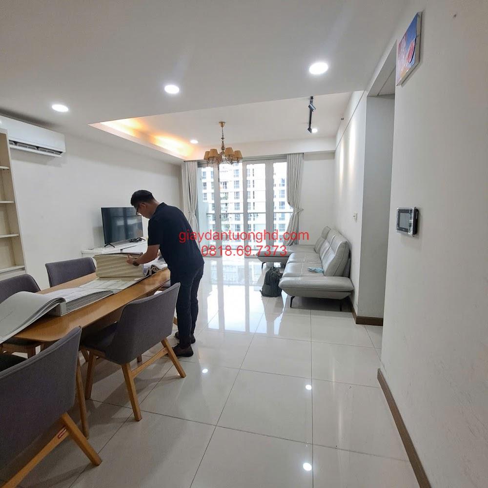 Nhân viên đang tư vấn chọn mẫu giấy dán tường trơn tại phòng khách căn hộ chung cư