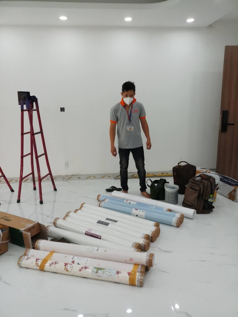 Kỹ thuật viên tập kết vật tư cuộn giấy dán tường Hàn Quốc và thang nhôm tại công trình căn hộ