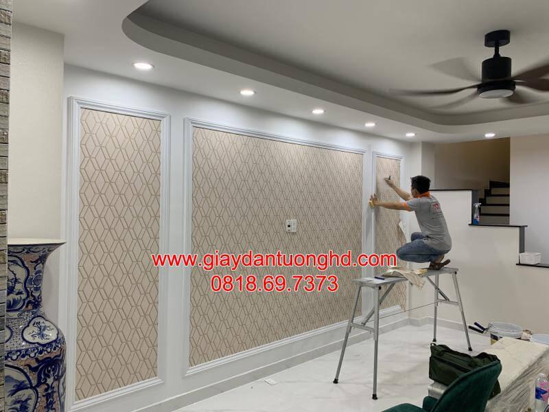 Thợ đang tỉ mỉ thi công dán giấy dán tường họa tiết hình học tối giản bên trong khung phào chỉ phòng khách.