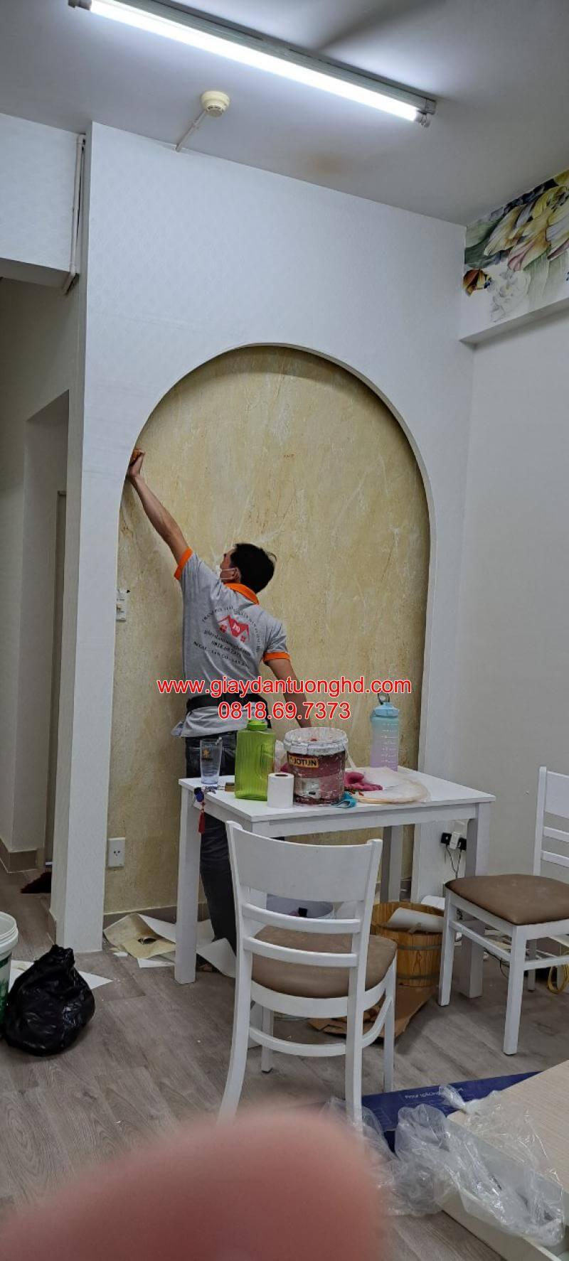 Cận cảnh quá trình thi công tỉ mỉ mẫu giấy dán tường họa tiết vân đá marbờ màu vàng kem cho khu vực ô vòm trang trí, một giải pháp tạo điểm nhấn kiến trúc độc đáo, giúp không gian phòng ăn trở nên ấm cúng và sang trọng hơn.