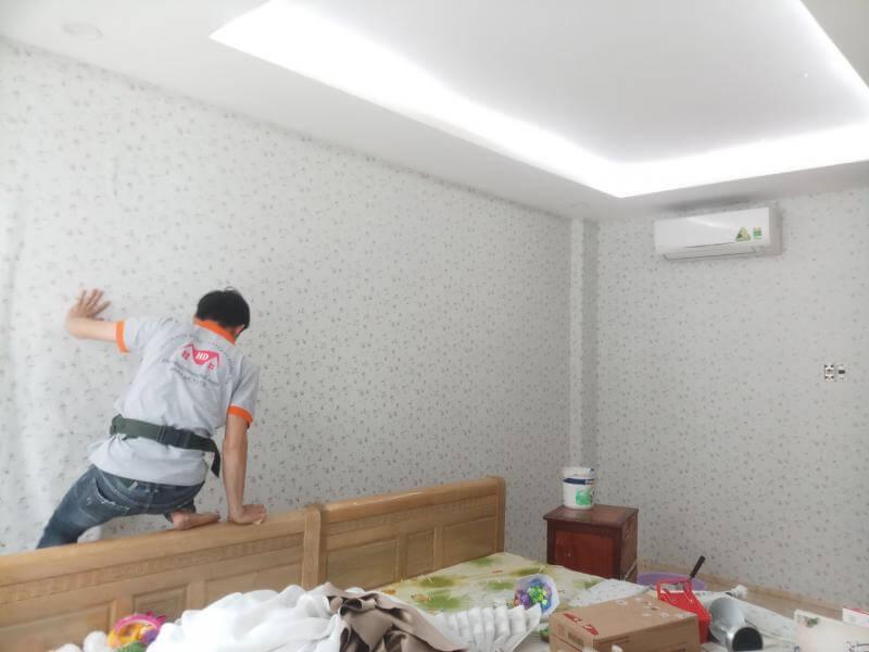Thợ thi công đang khéo léo định hình tấm giấy dán tường hoa nhí phong cách Hàn Quốc cho không gian phòng ngủ.